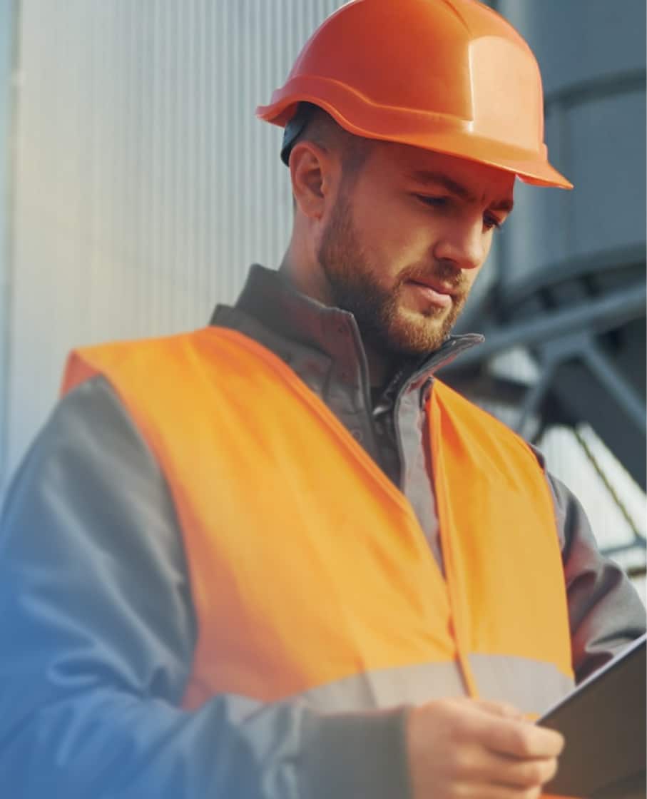 A man with a hard hat looking at a clipboard.